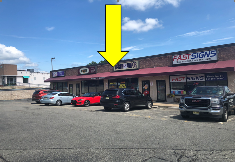 A row of cars are parked in front of a fast signs store.