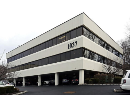 A row of cars are parked in front of a brick building.