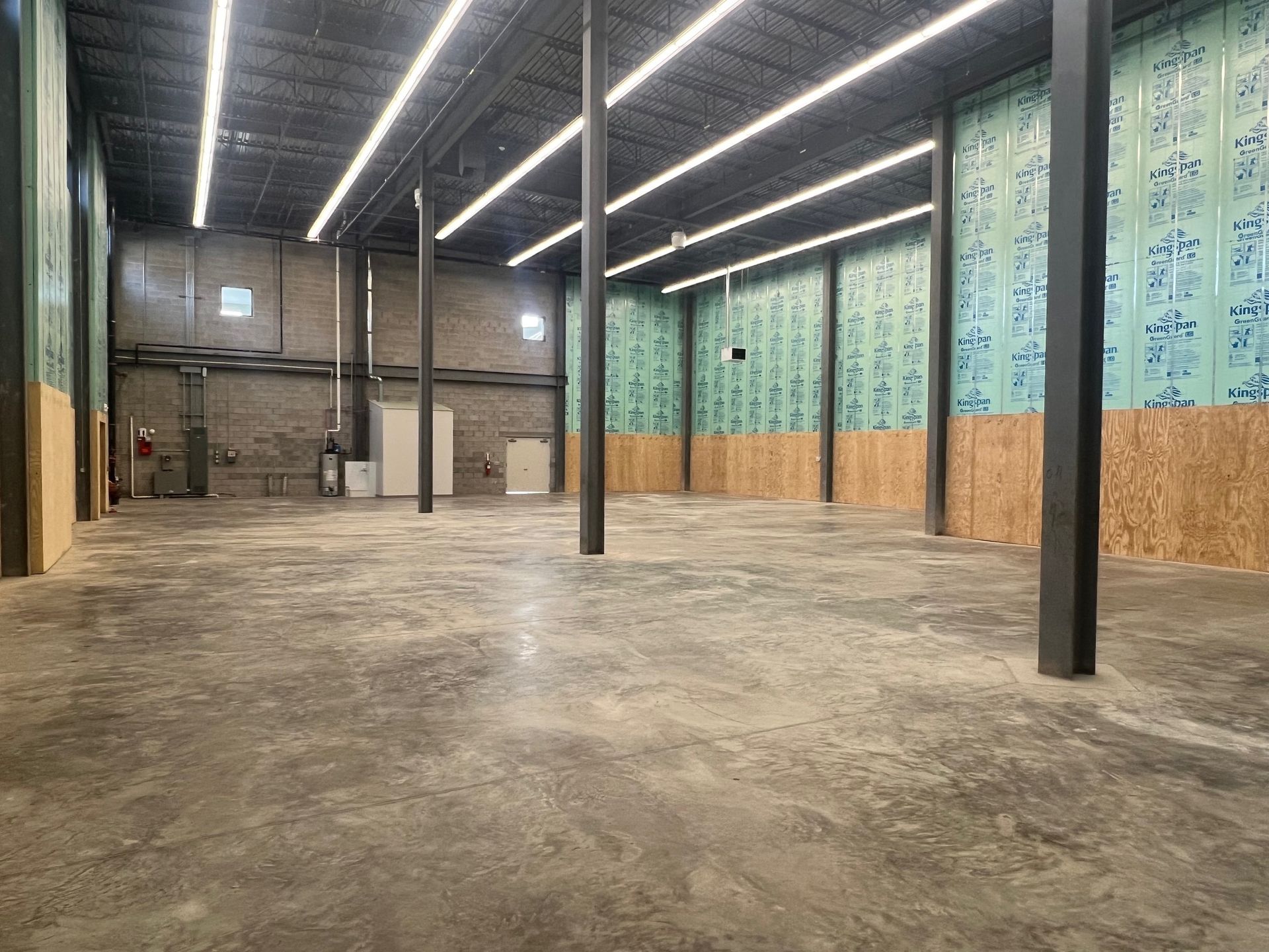 Interior of a large, empty commercial space with exposed columns, concrete floor, and partially finished walls.