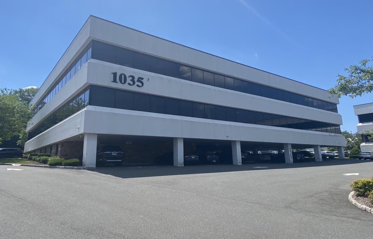 A row of cars are parked in front of a brick building.