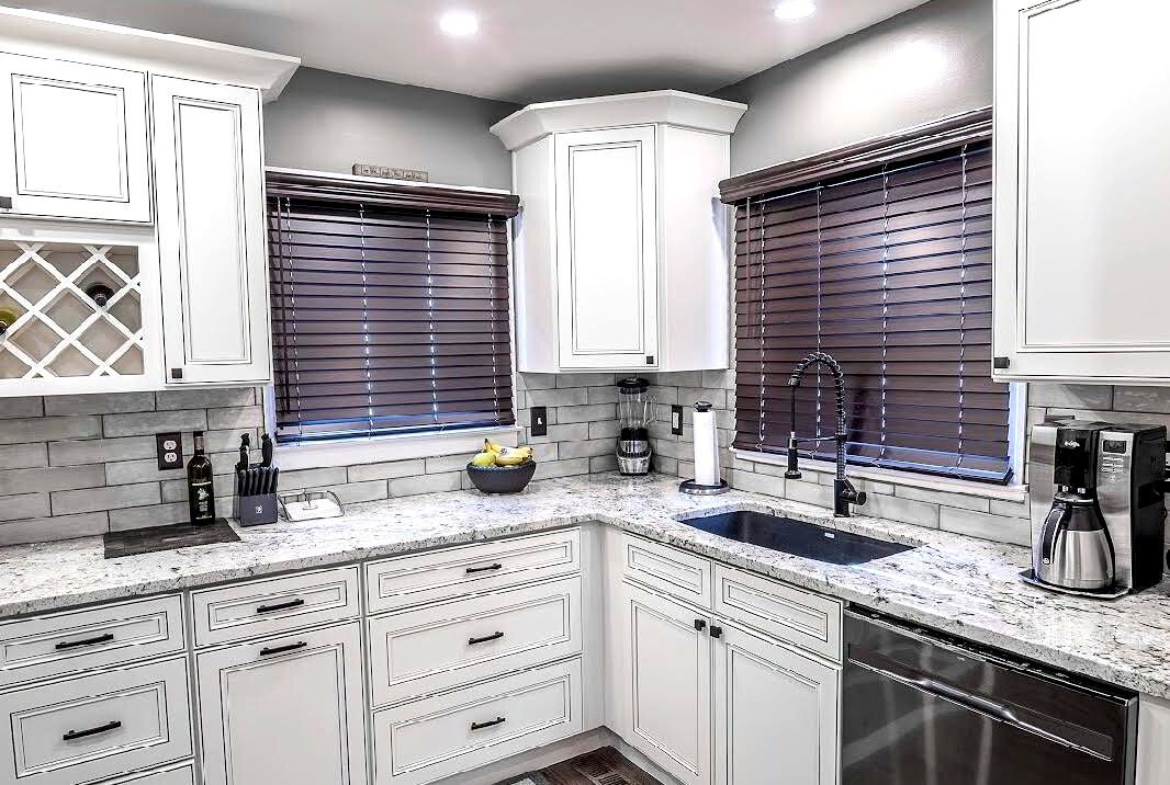 A kitchen with white cabinets , granite counter tops , and stainless steel appliances.