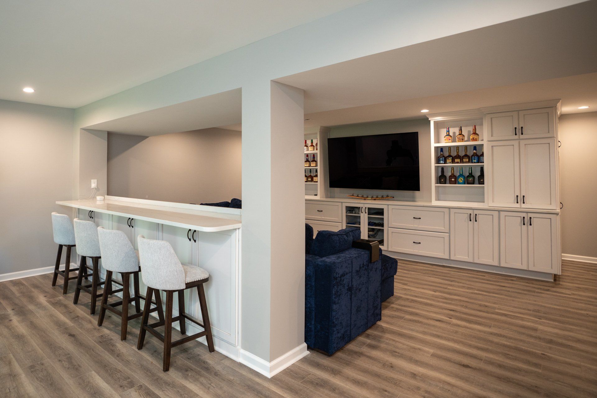 A basement with a bar , stools , and a television.