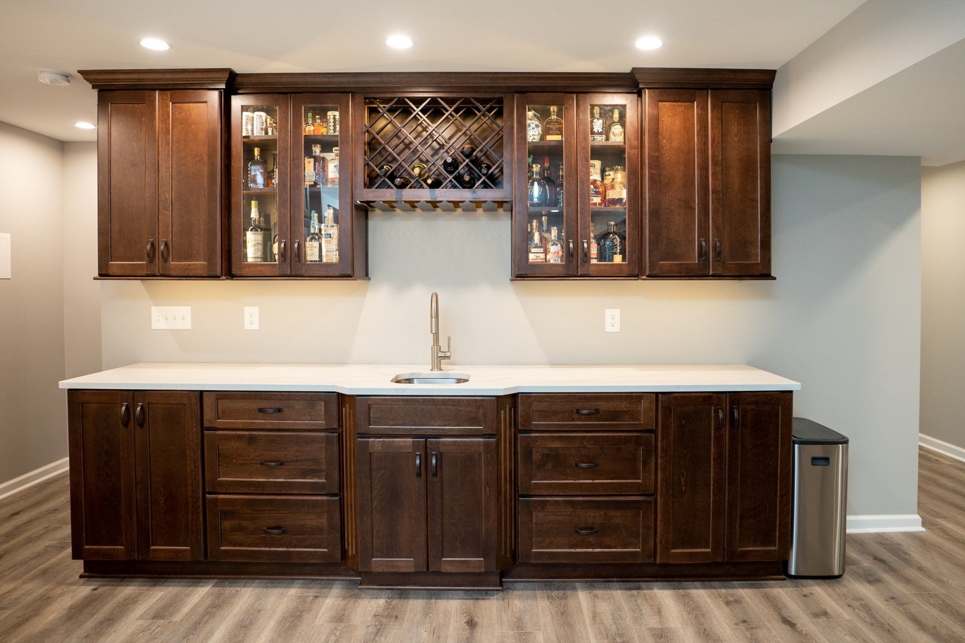 A kitchen with wooden cabinets , a sink , and a wine rack.