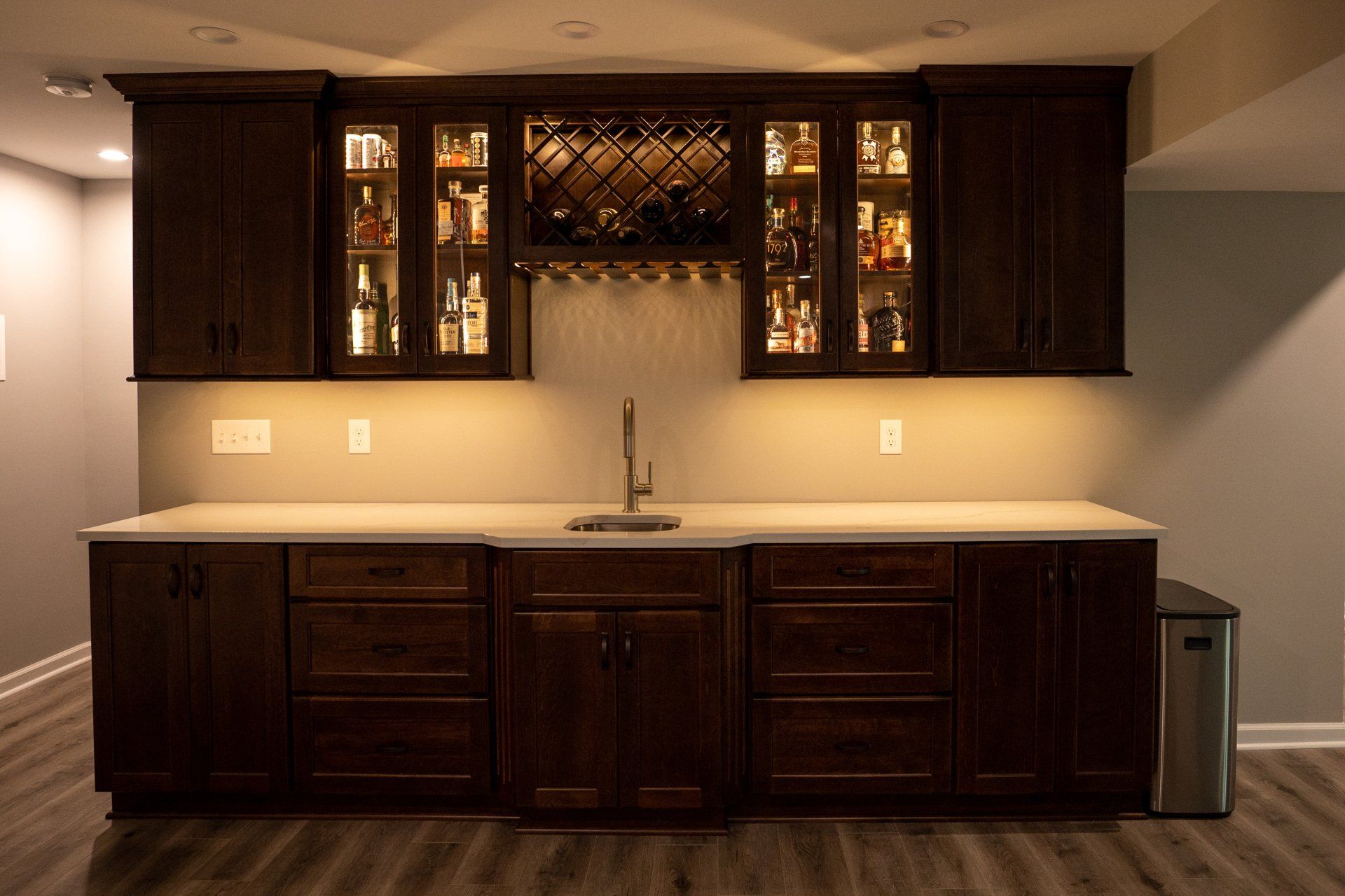 A kitchen with wooden cabinets , a sink , and a wine rack.