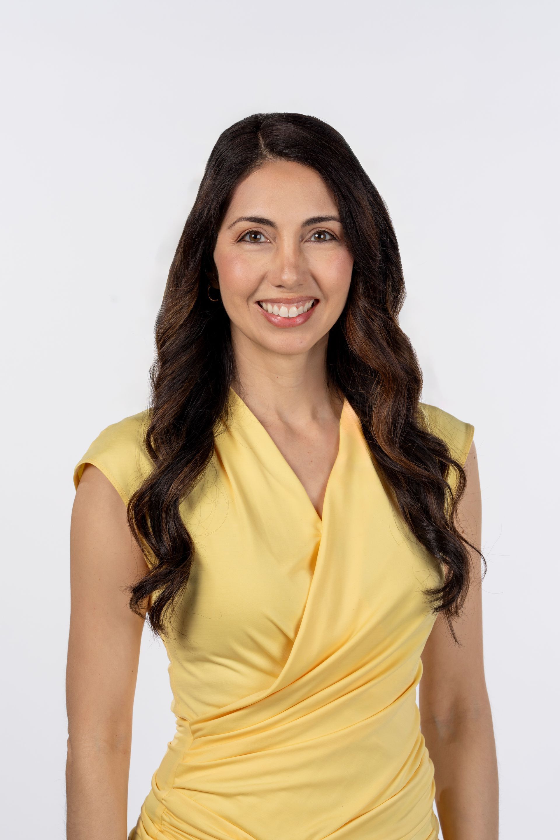 A woman in a yellow dress is smiling for the camera.