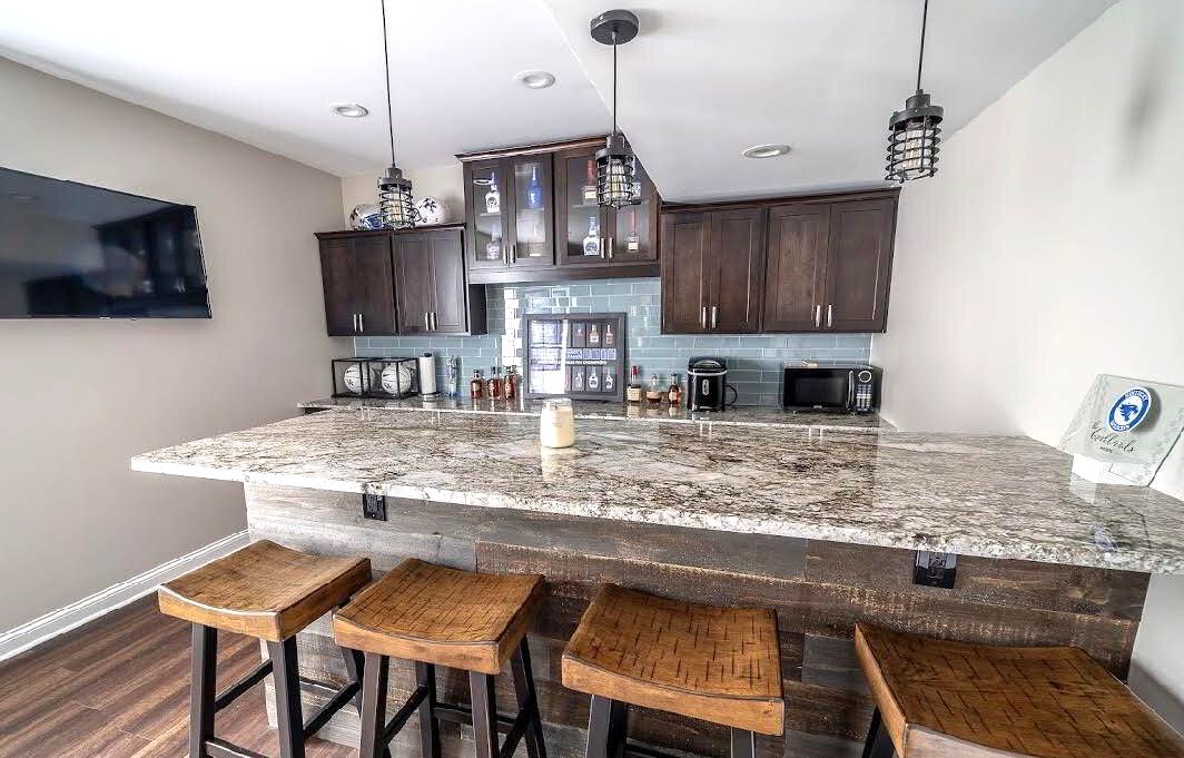 A kitchen with a large granite counter top and stools.