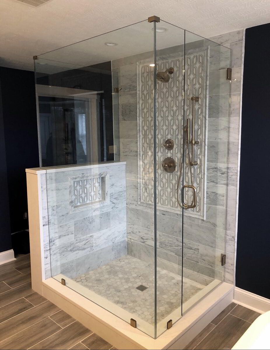 A bathroom with a walk in shower with a glass door.