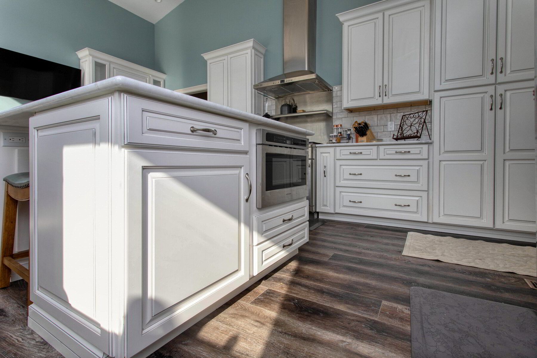 A kitchen with white cabinets and a large island in the middle.