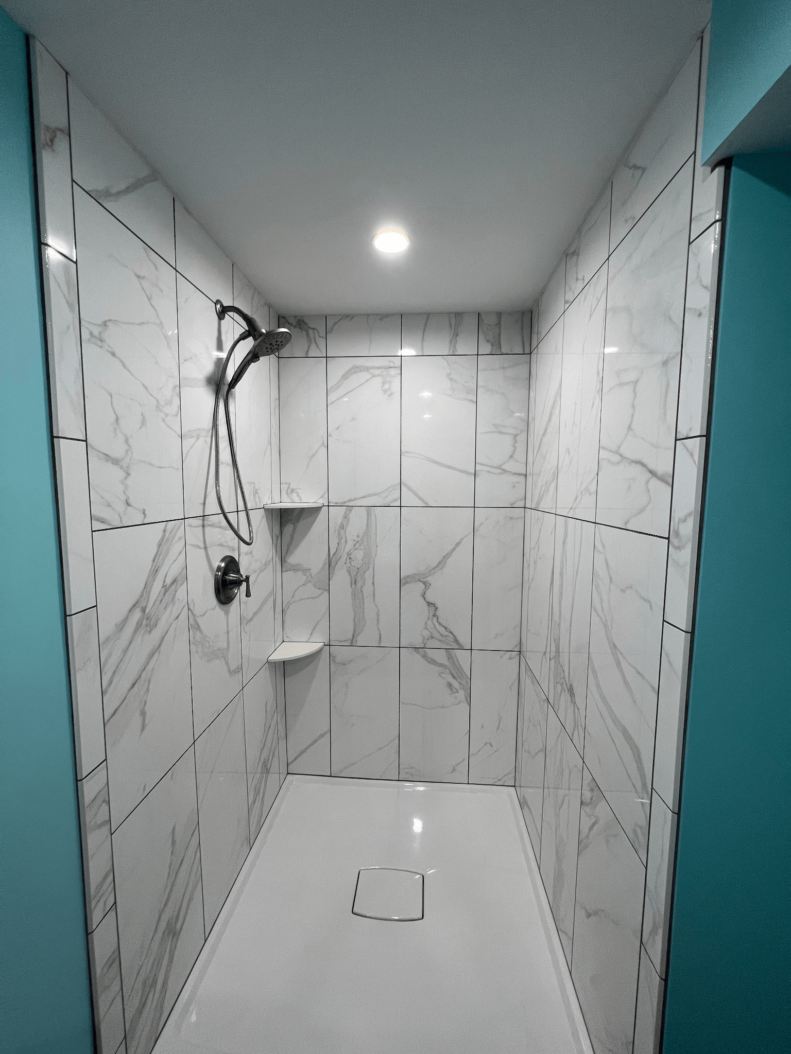 A bathroom with marble walls and a walk in shower.