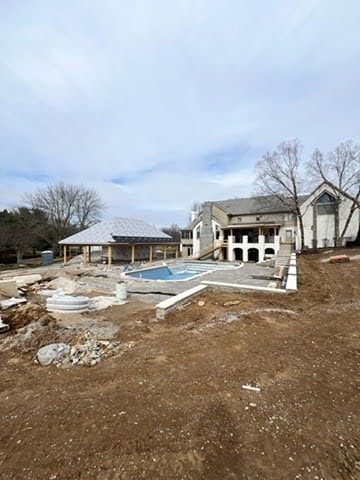 A large house is being built with a swimming pool in the backyard.