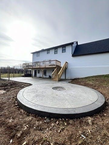 A large white house with a circular concrete patio in front of it.