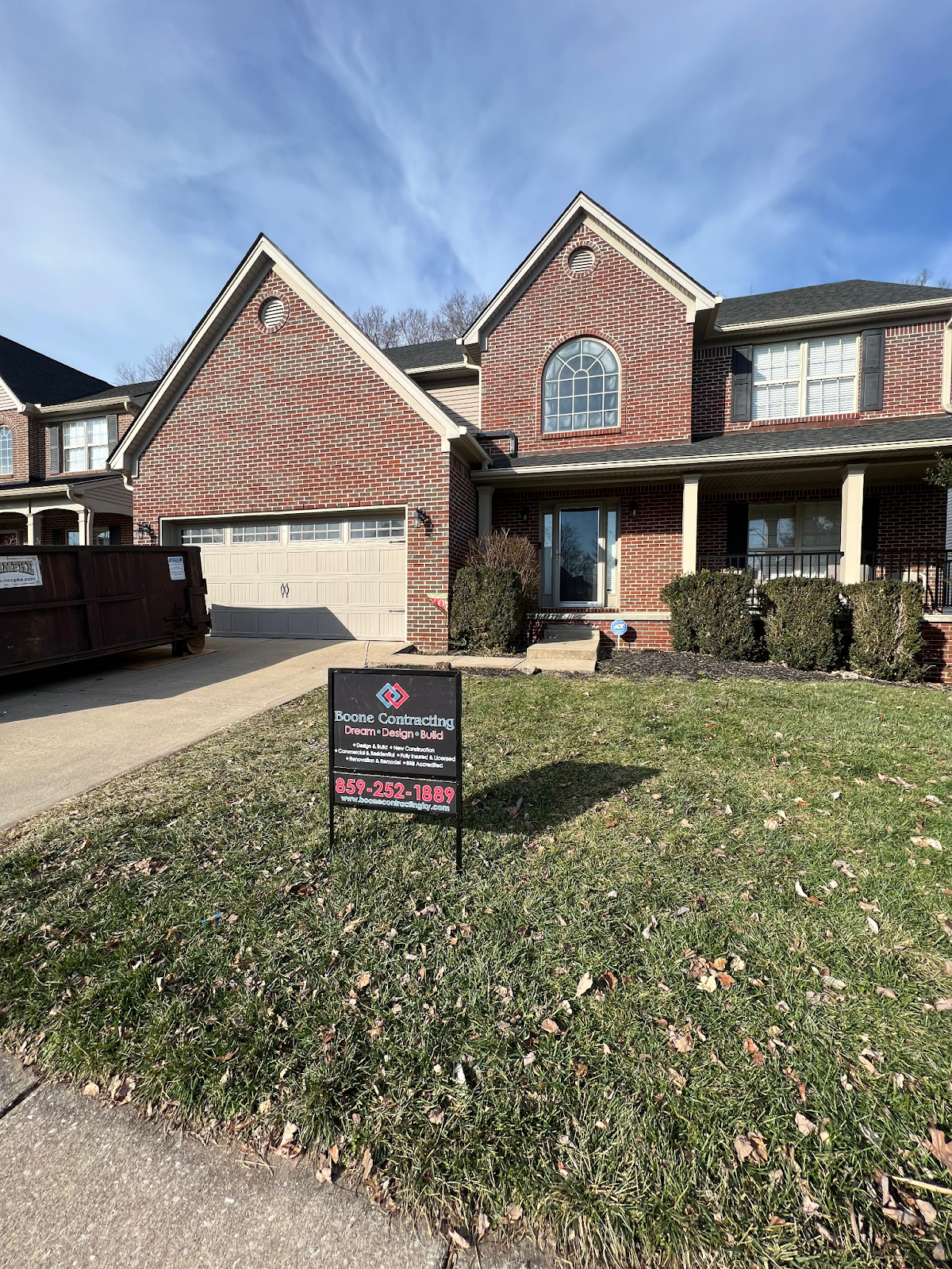 A large brick house with a for sale sign in front of it.