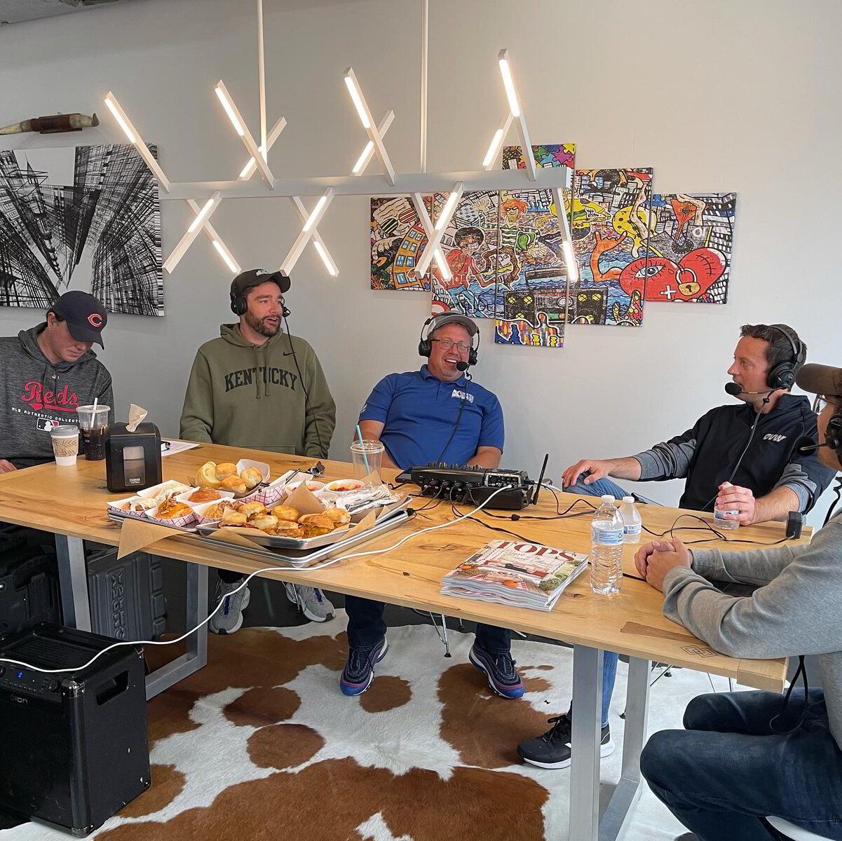 A group of men are sitting around a table with a cow print rug