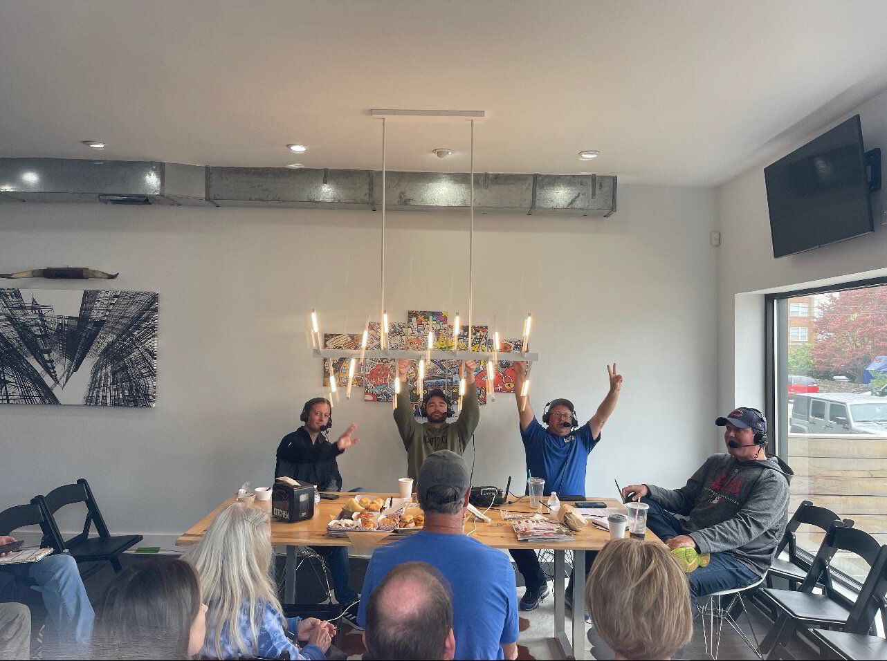 A group of people are sitting around a table with their arms in the air.