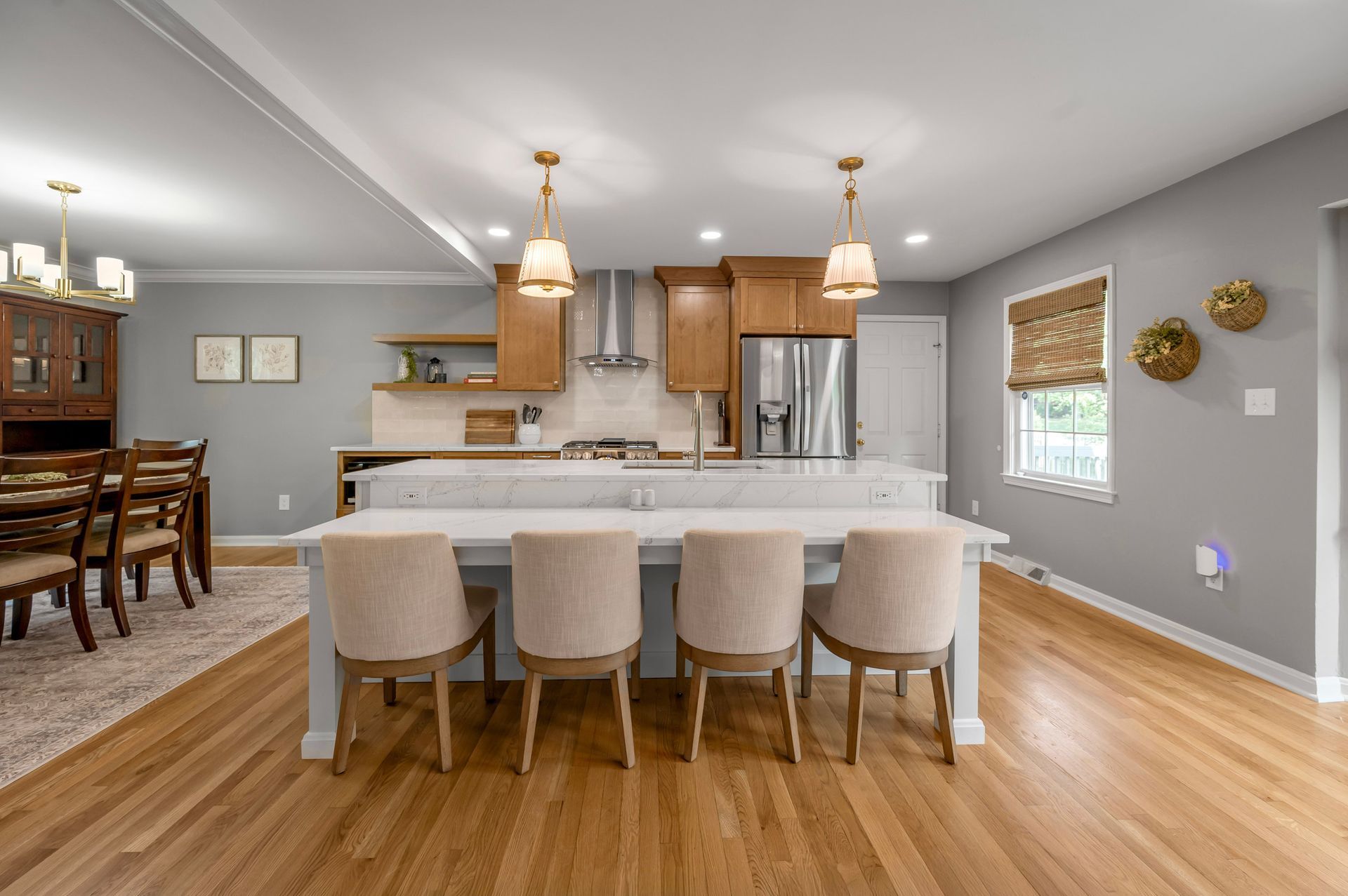 Modern kitchen with wood cabinets, island with chairs, and hardwood floors.