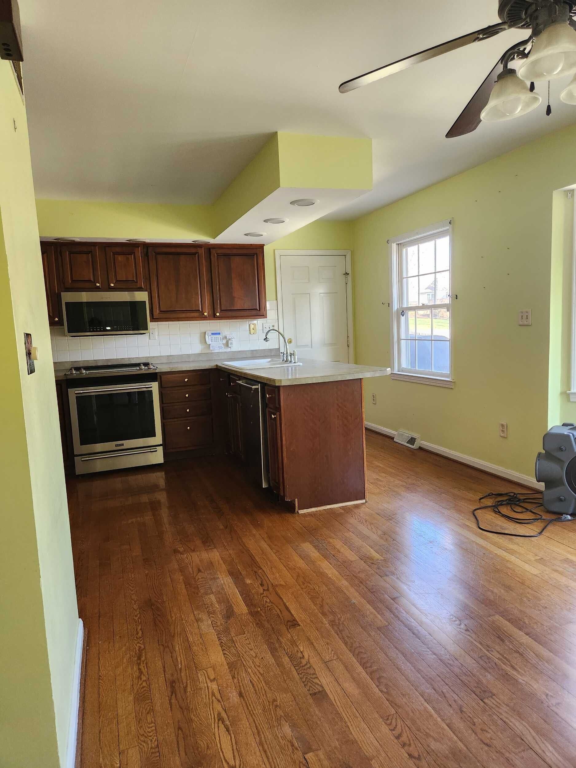 Kitchen with dark cabinets, light countertops, hardwood floor, and green walls.