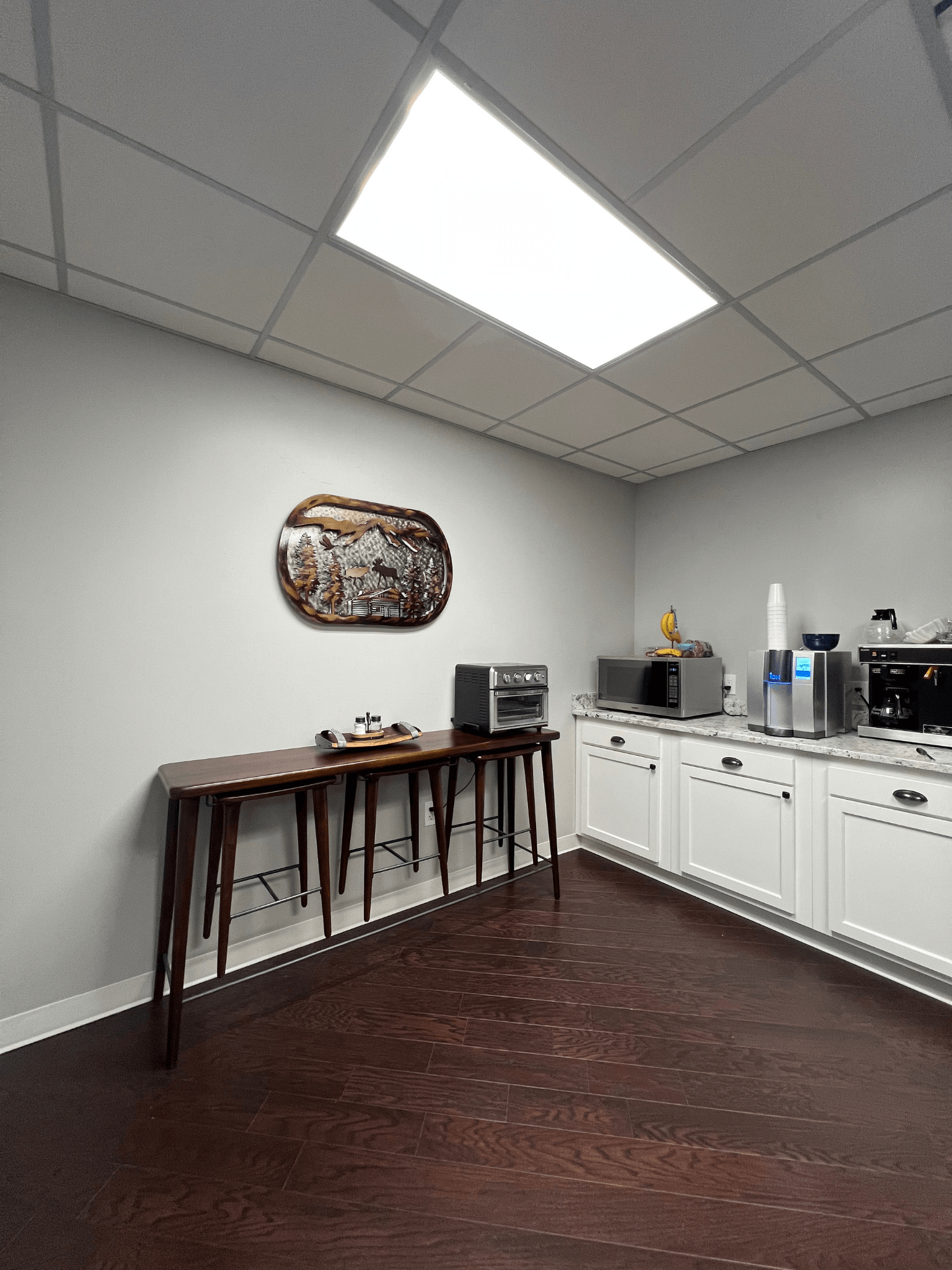A kitchen with white cabinets and a tray on the wall