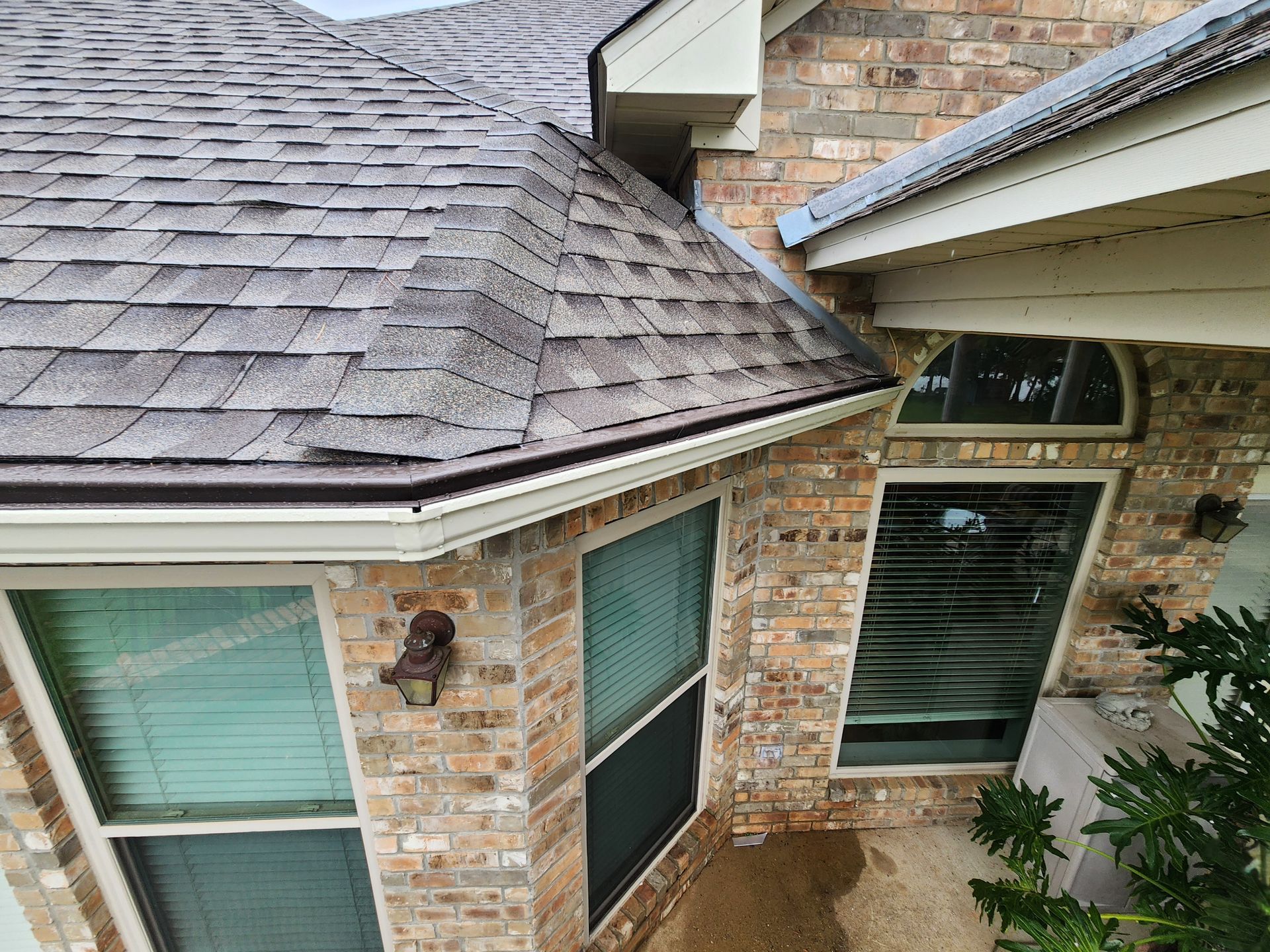 An aerial view of a brick house with a roof and windows.