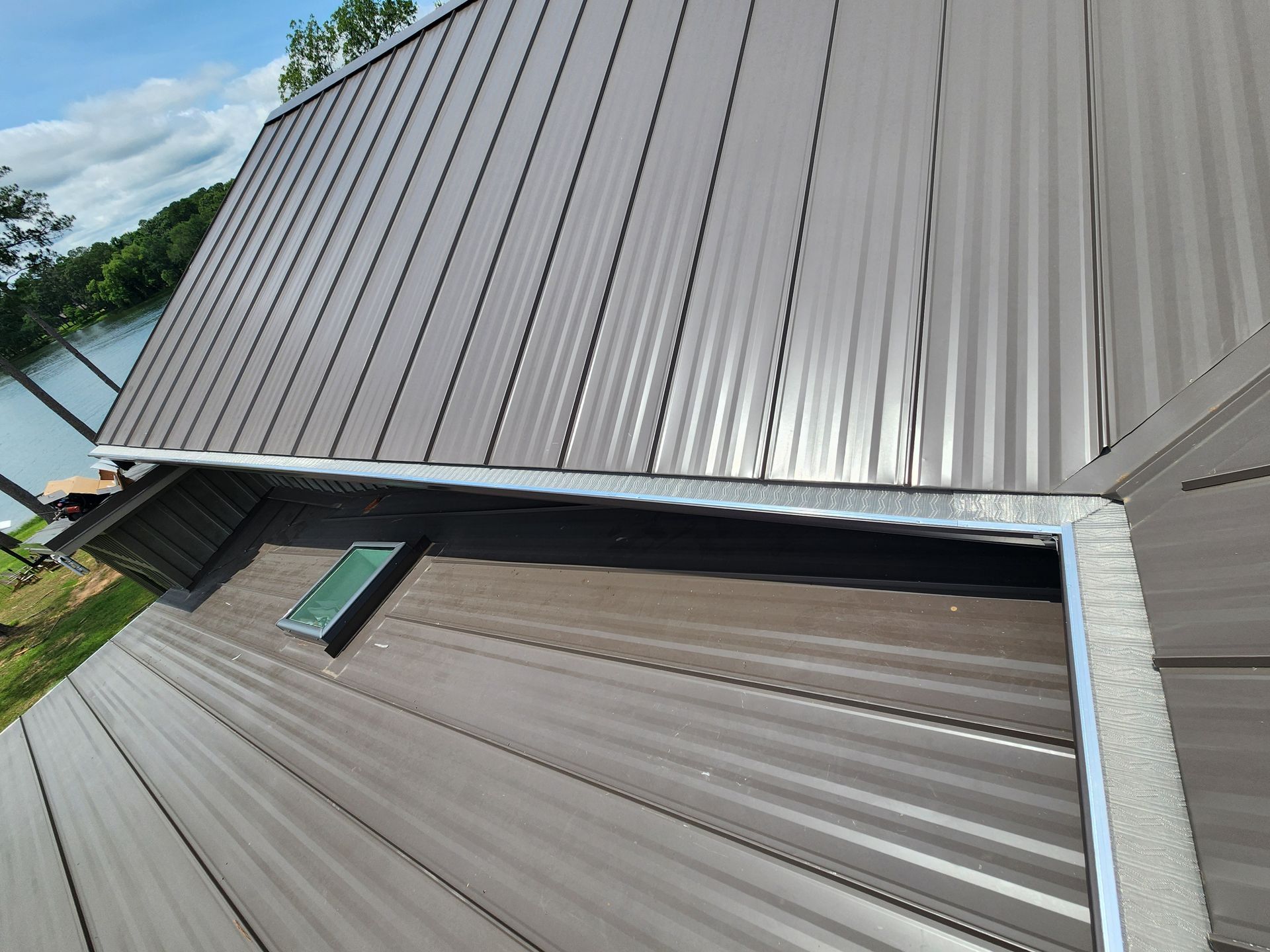 A brown metal roof with a skylight on the side of it.