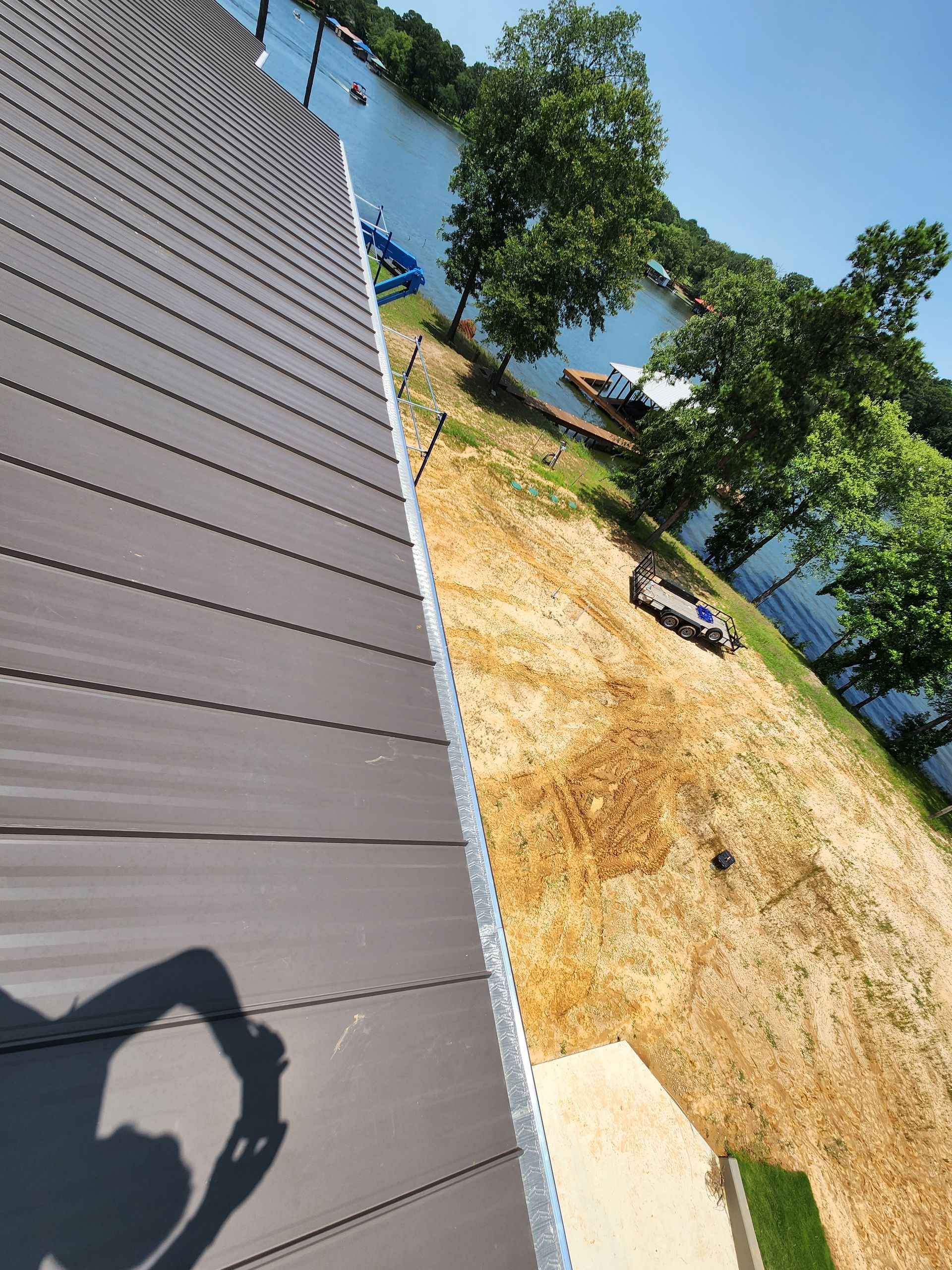 A person is taking a picture of a roof with a lake in the background.