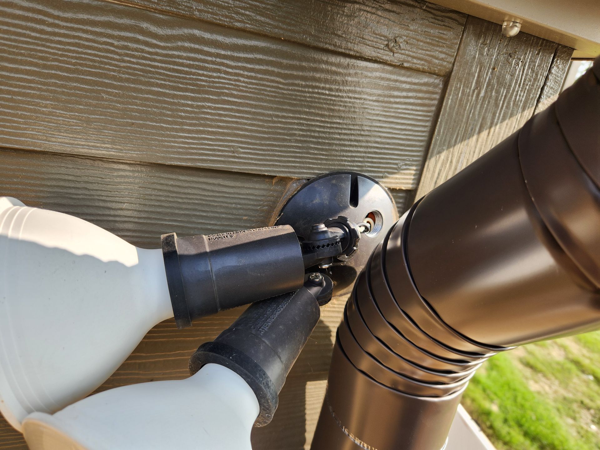 A person is installing a gutter on the side of a house.