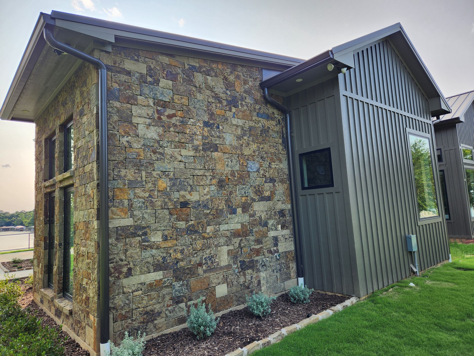 A small house with a stone wall and a metal roof.