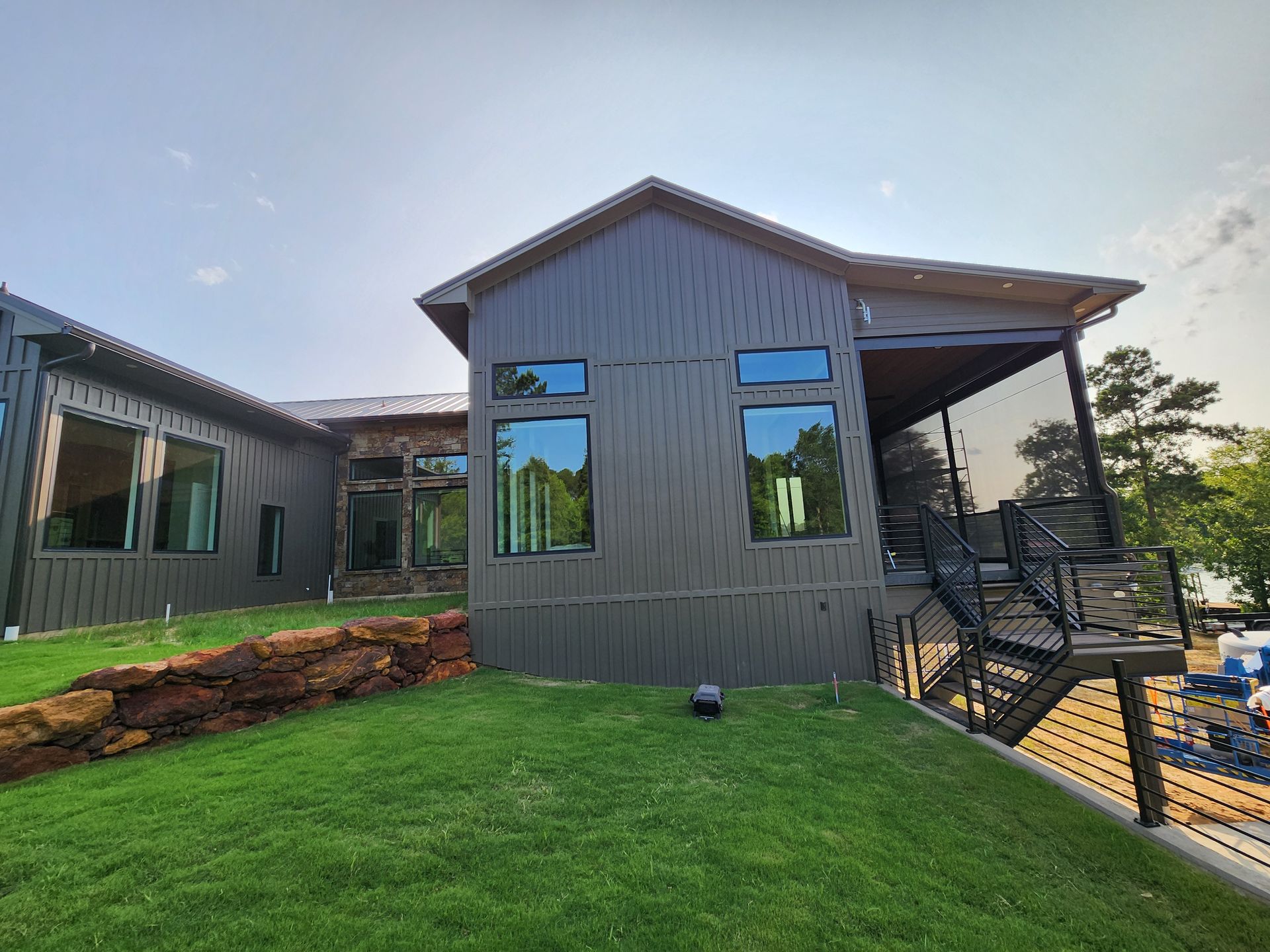 A large house with a lot of windows is sitting on top of a lush green hill.