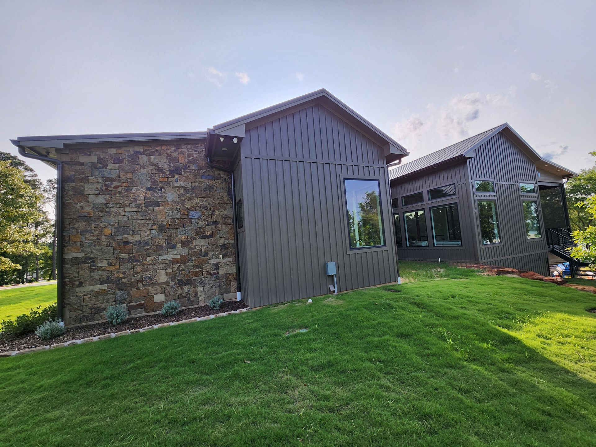 A large house with a lot of windows is sitting on top of a lush green hill.