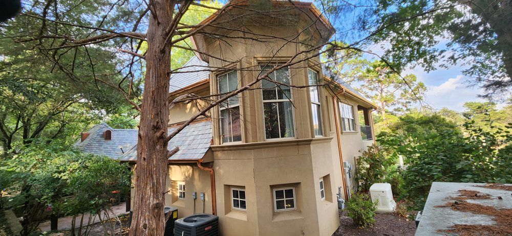 A house with a tower on top of it is surrounded by trees.