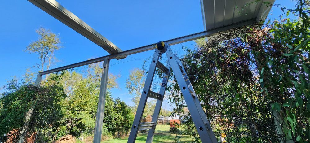 A ladder is sitting on top of a metal structure in a garden.
