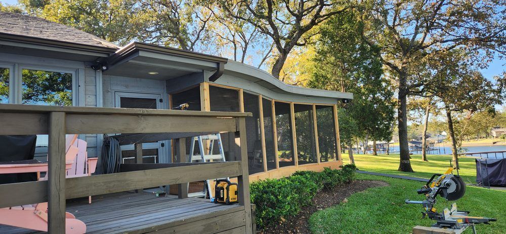 A house with a screened in porch and a wooden deck.