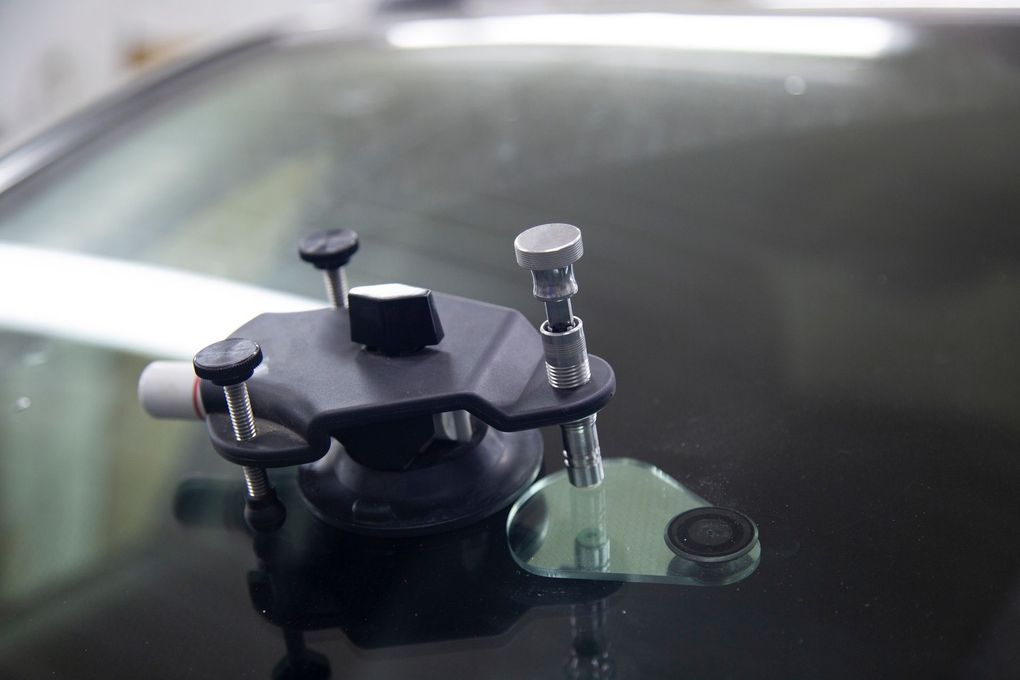 Windshield crack repair kit on a car, injecting resin to mend glass damage.