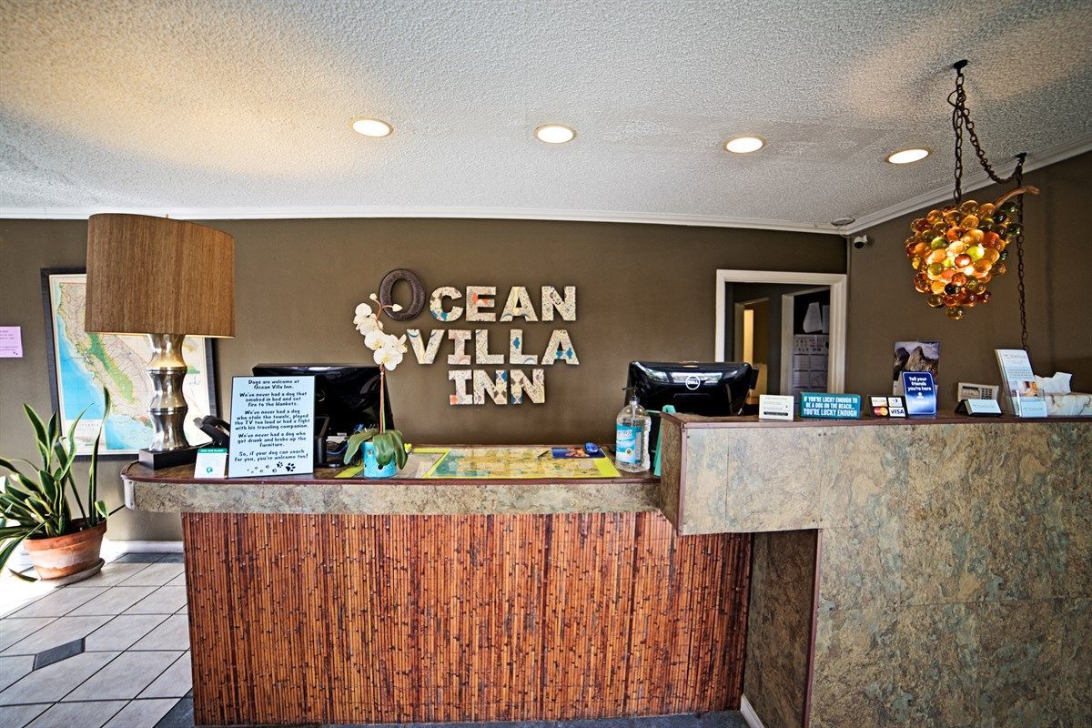 Ocean Villa Inn reception desk. Brown textured counter with the hotel name above.