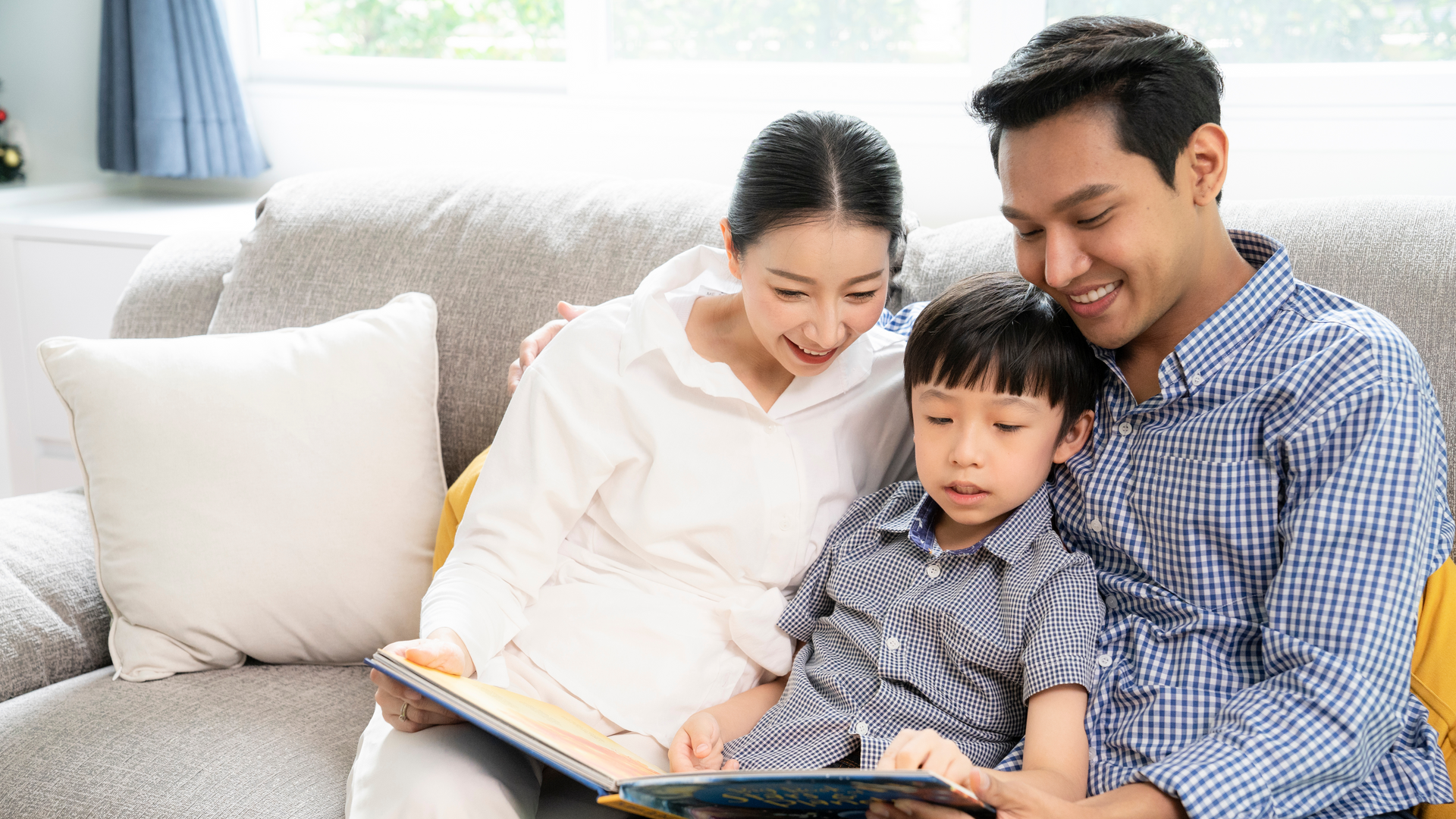 A family is sitting on a couch reading a book together.