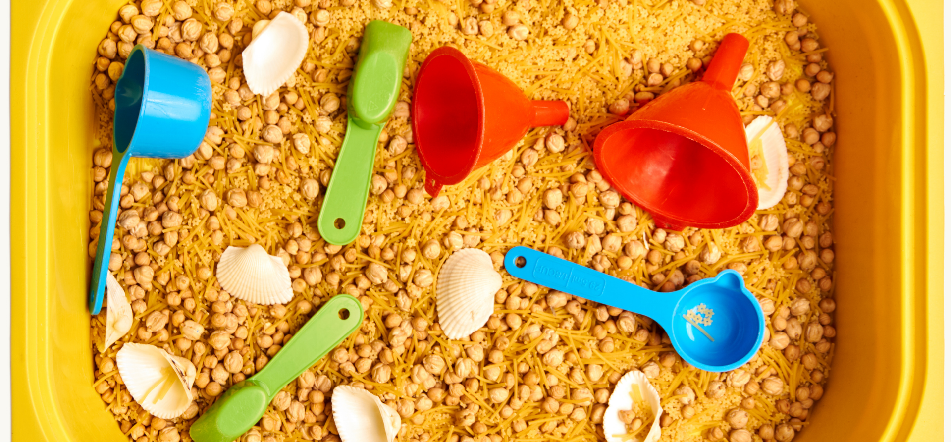 Yellow tray with grains, funnels, scoops, and shells.