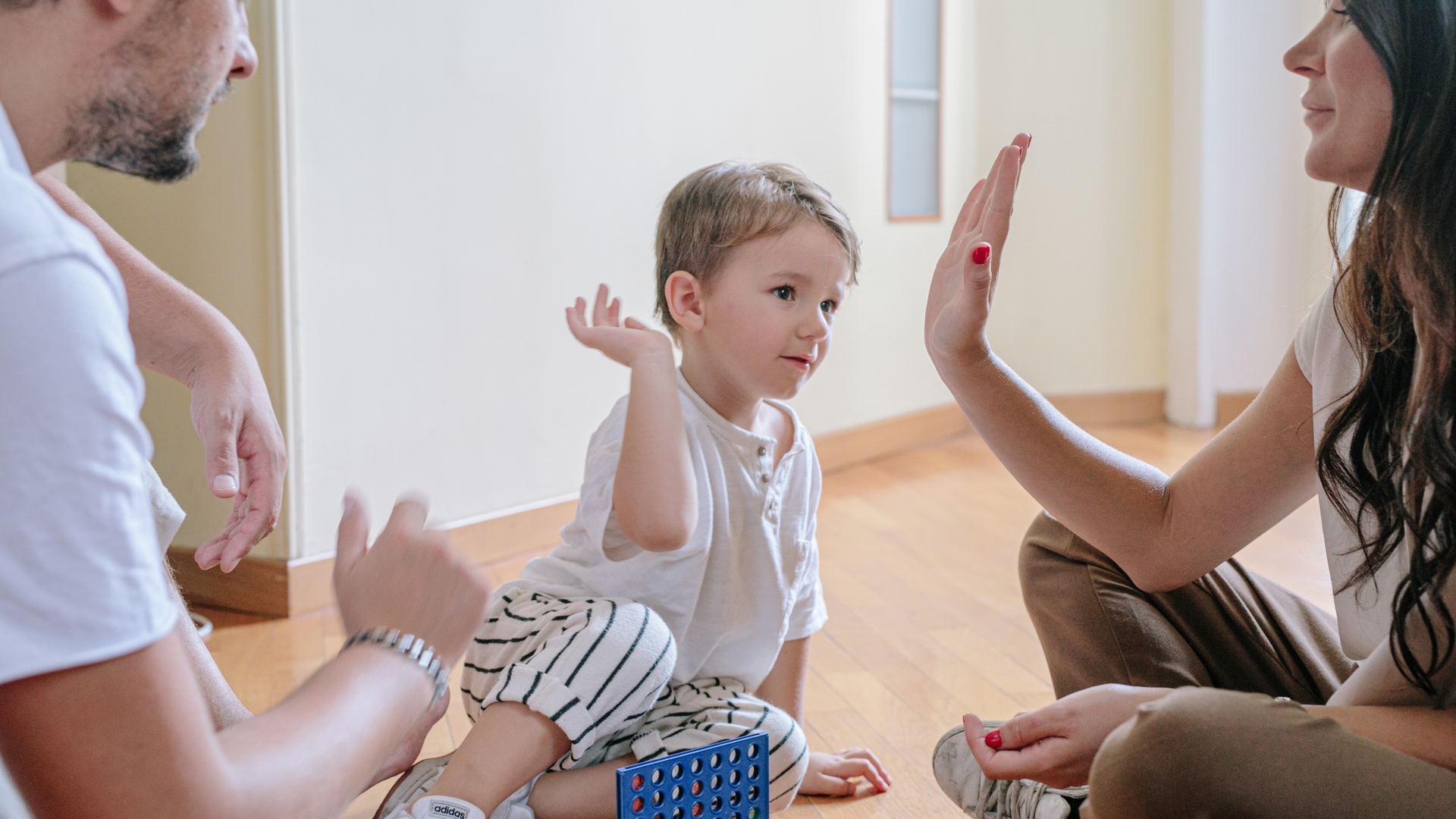 A family is sitting on the floor giving each other a high five.