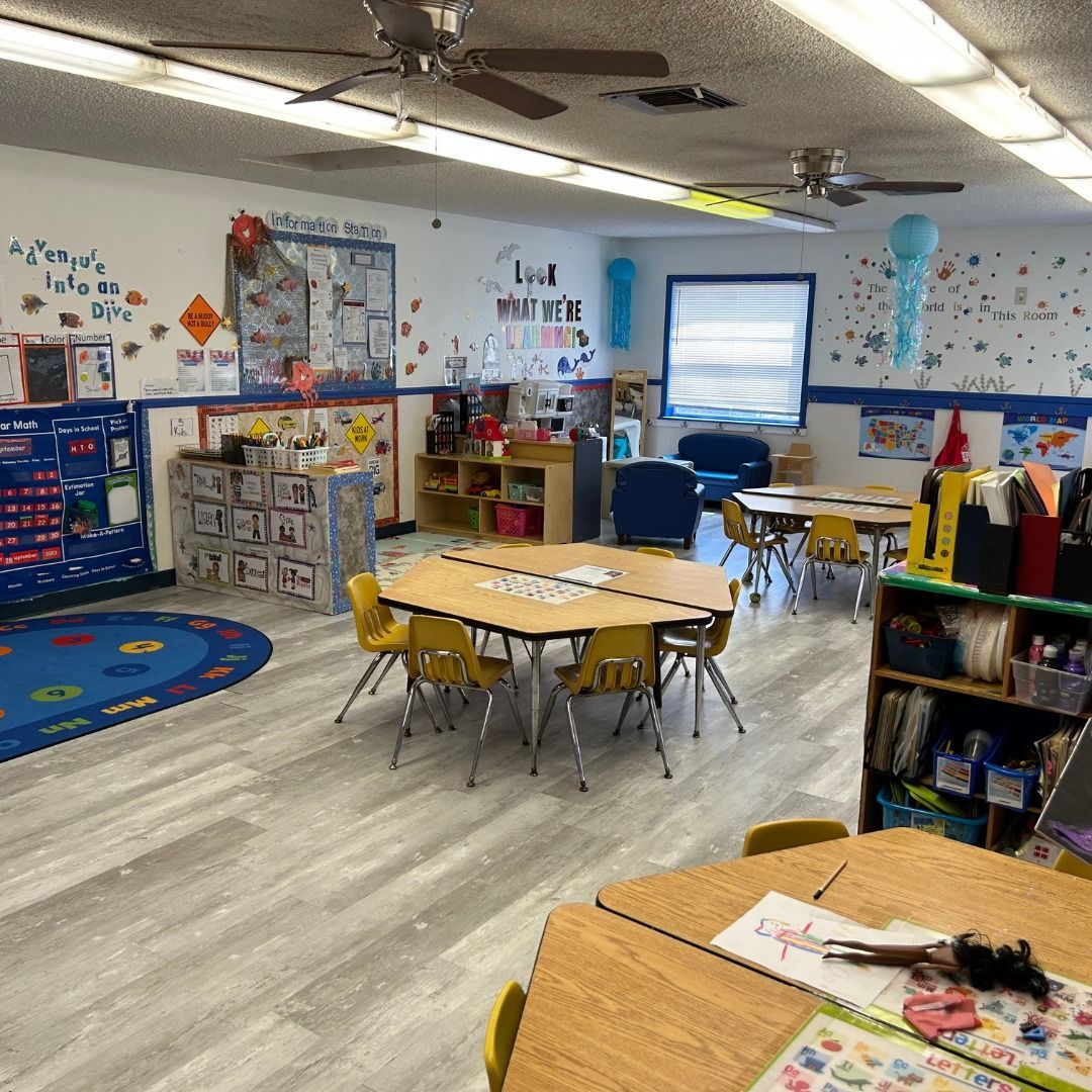 A classroom with tables and chairs and a ceiling fan.