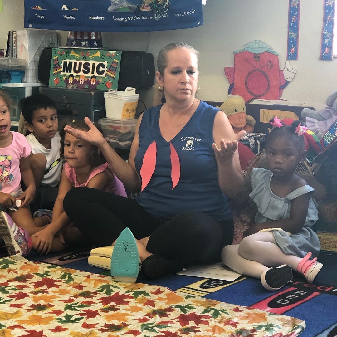 A woman sits on the floor in front of a sign that says music