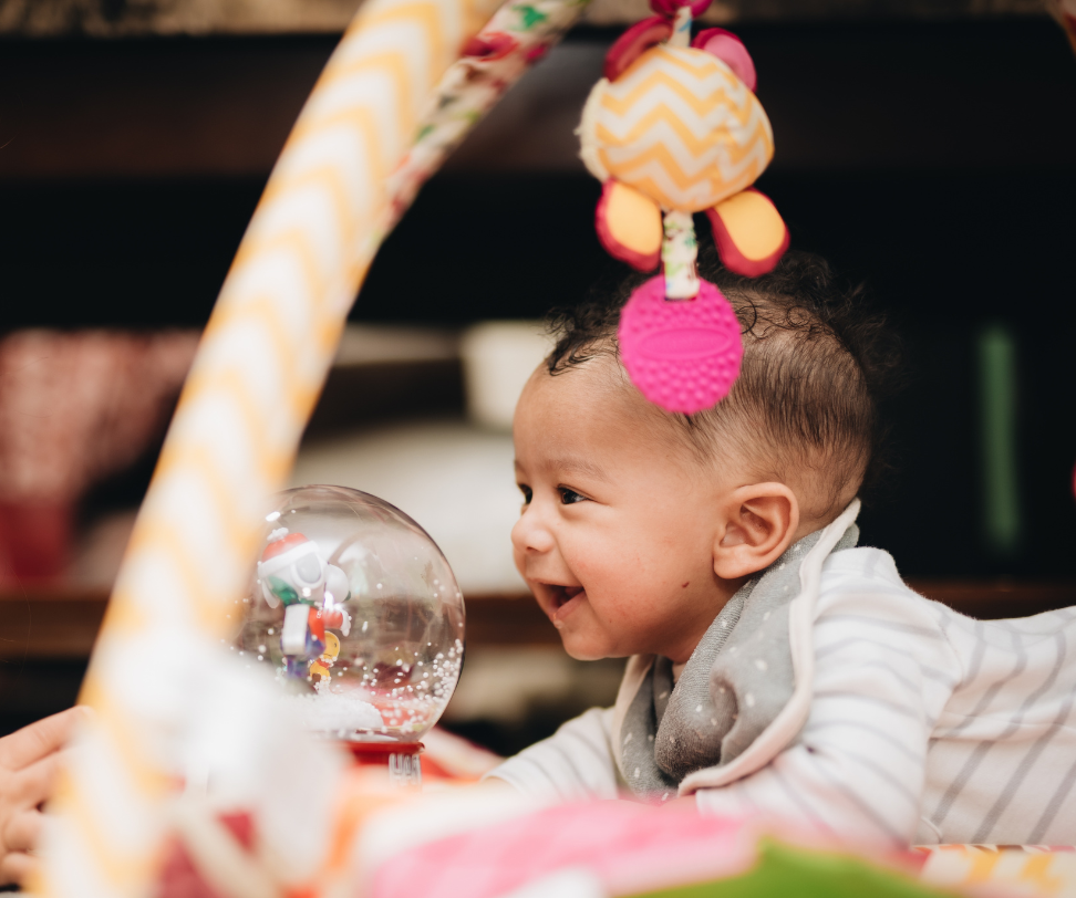 A baby is playing with a toy in a play mat.