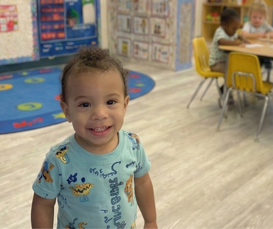 Teacher and two children playing with colorful blocks at a table in a classroom.