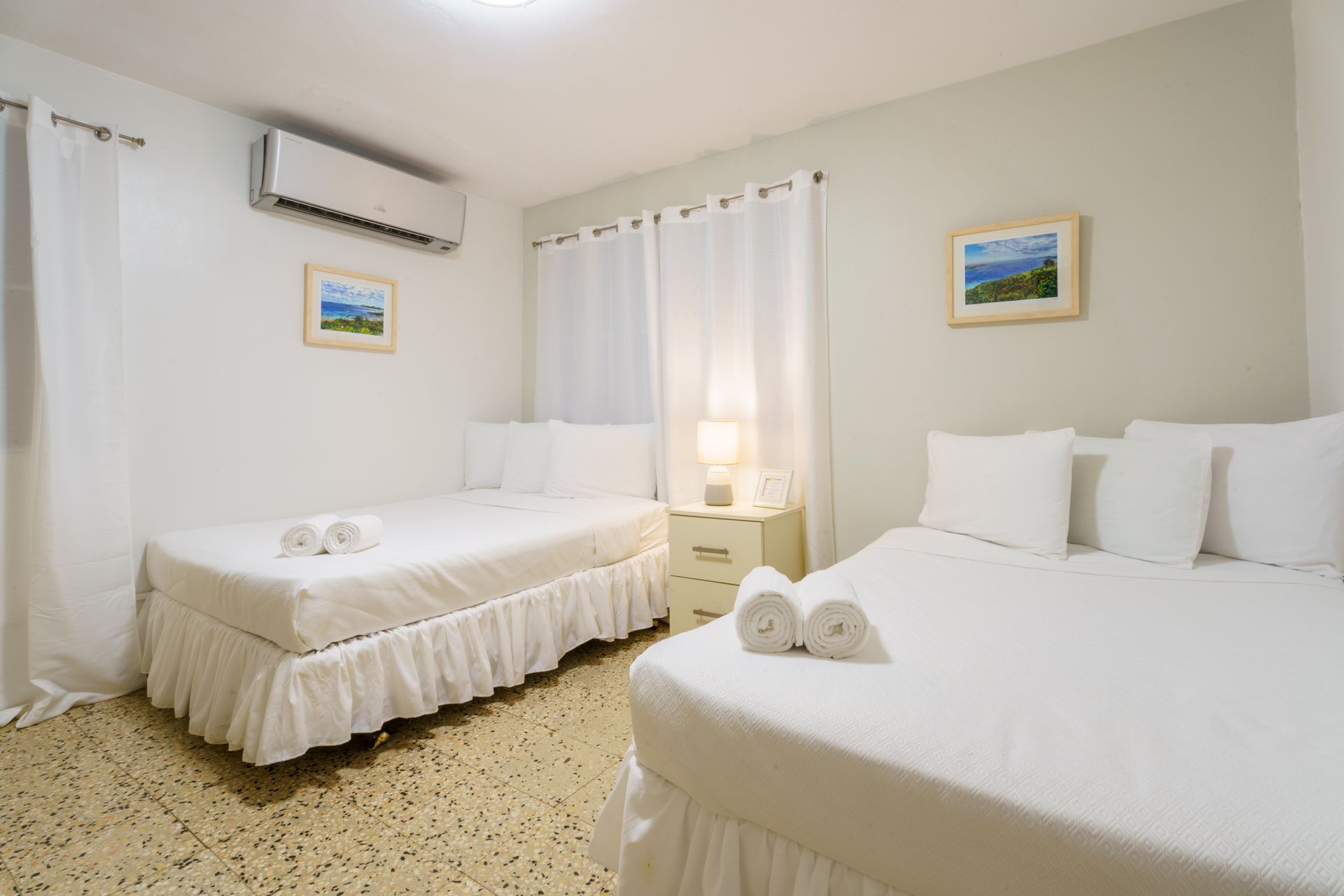 A hotel room with two beds and a nightstand.