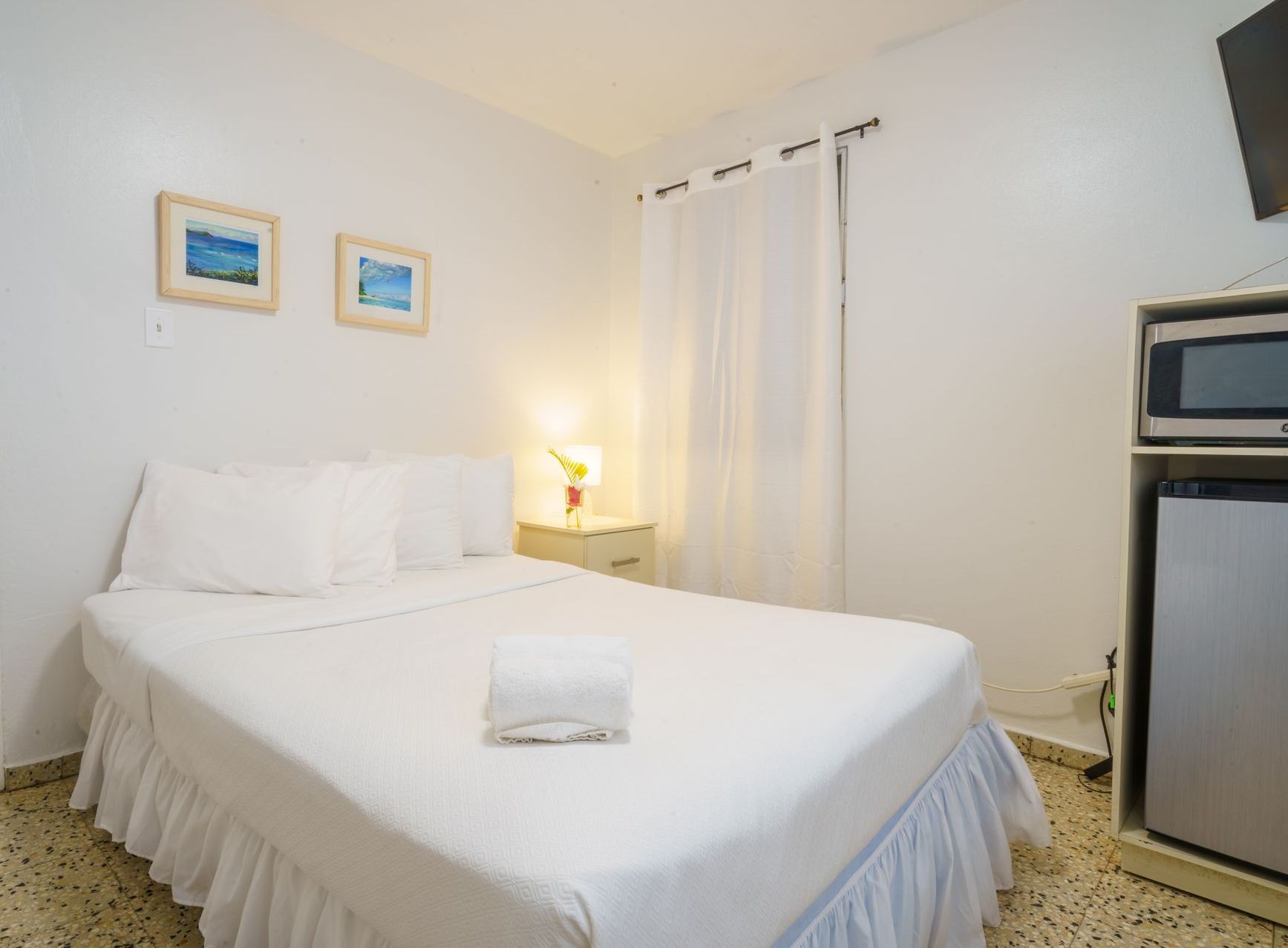 A hotel room with a bed , microwave , and refrigerator.