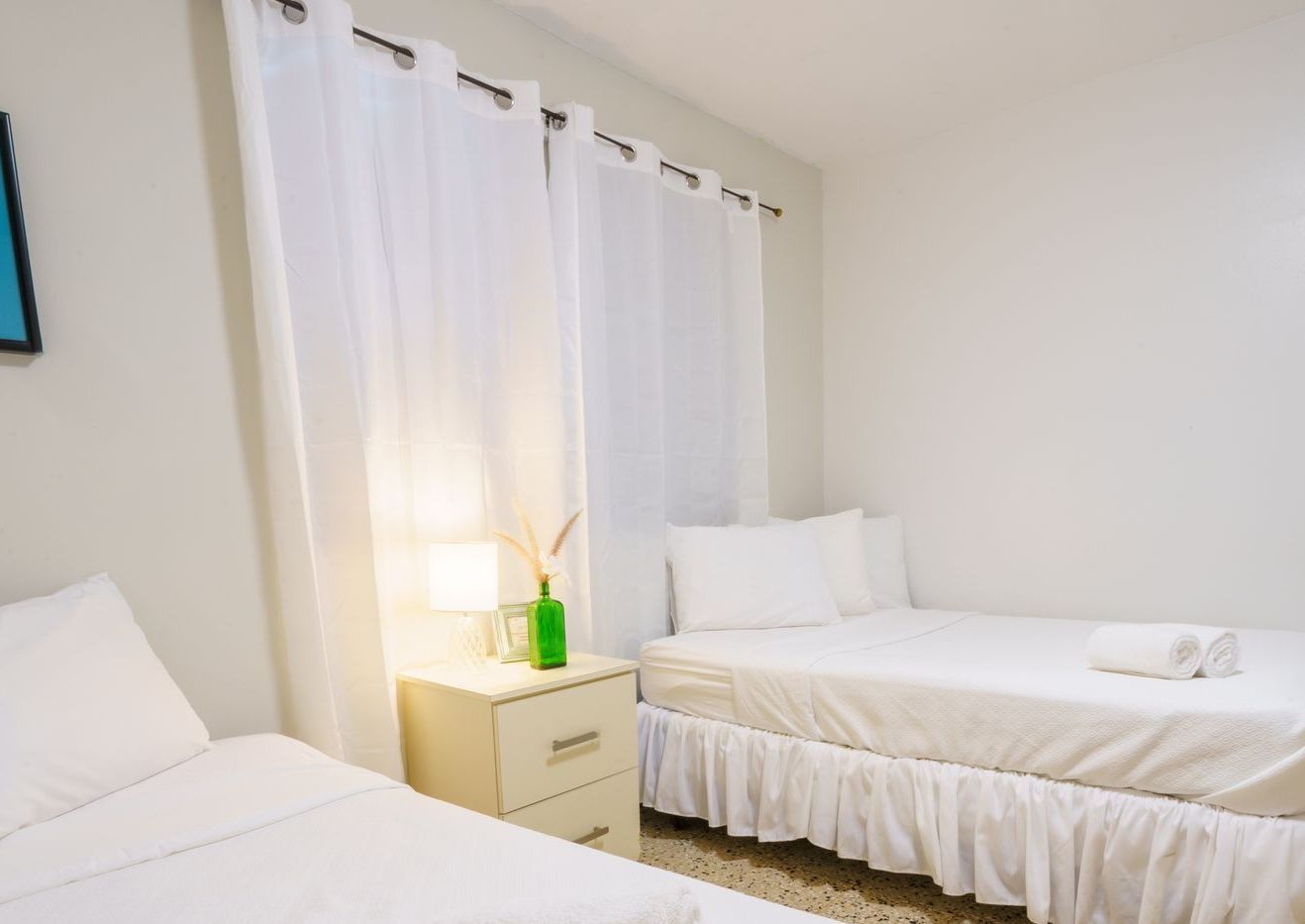 A bedroom with two beds and a nightstand.