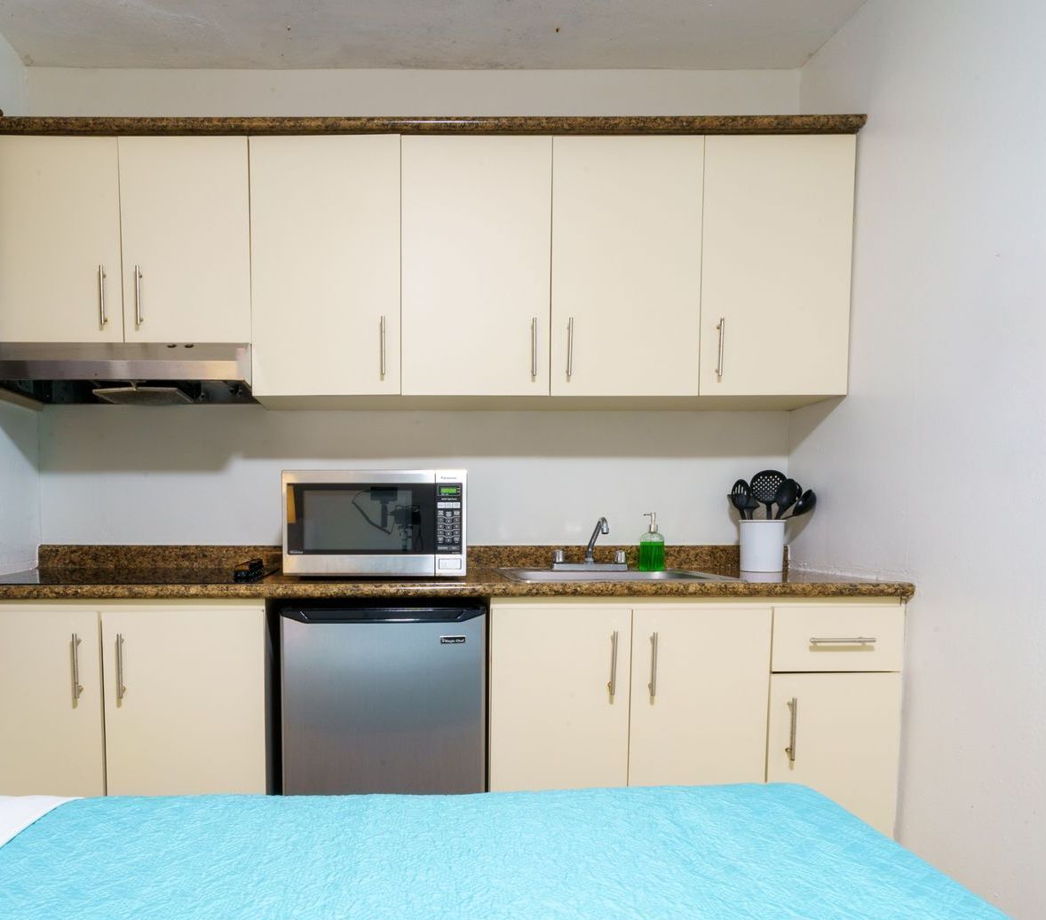 A kitchen with white cabinets and a stainless steel refrigerator
