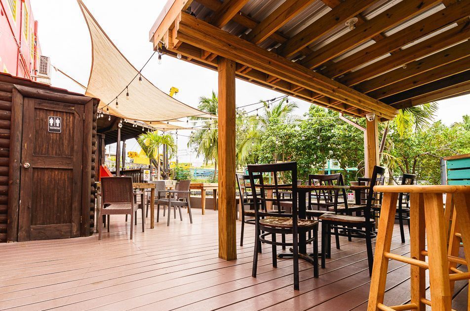 A wooden deck with tables and chairs under a canopy.