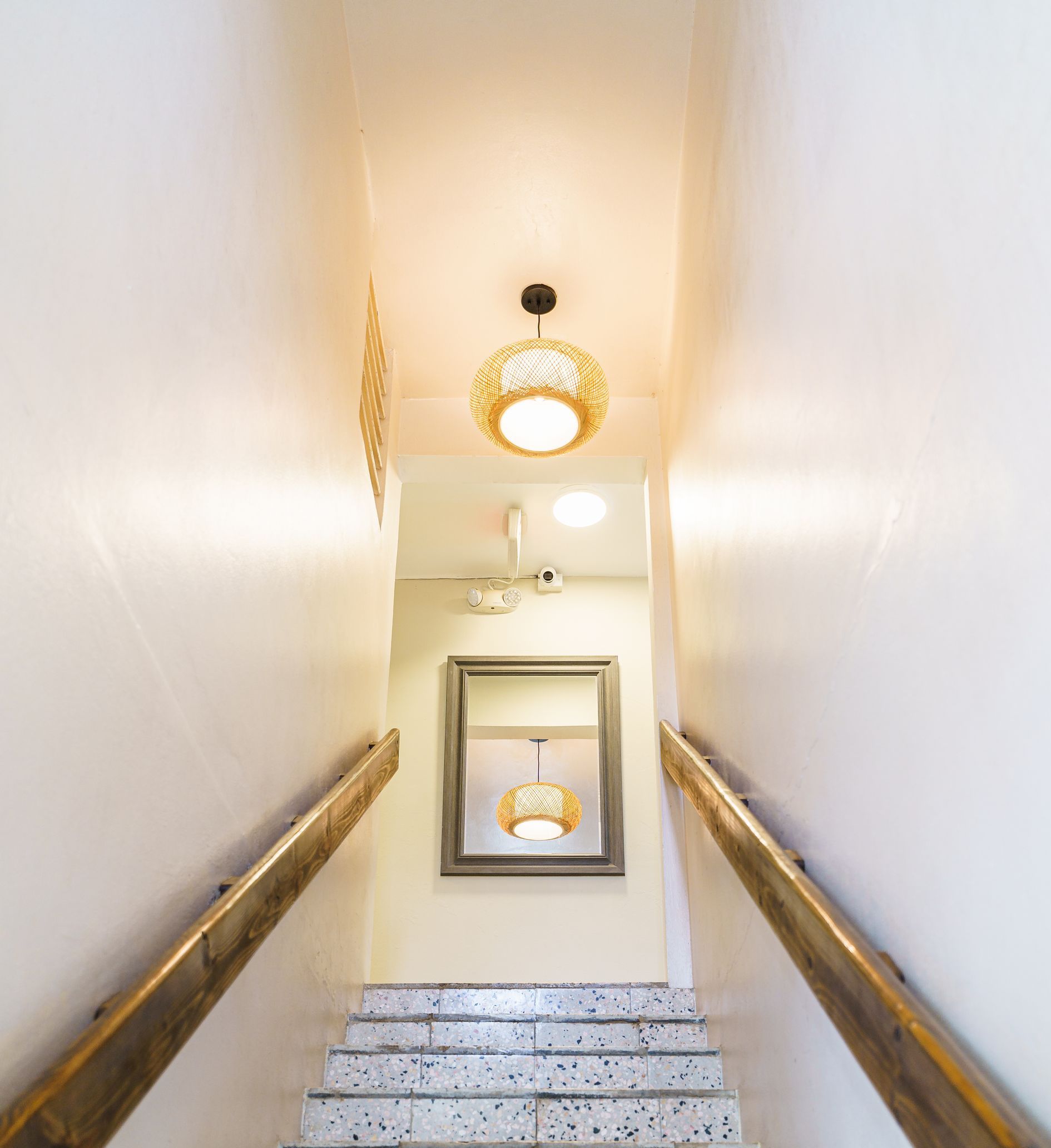 A staircase with a wooden railing and a mirror on the wall