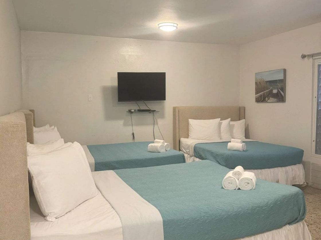 A hotel room with three beds and a flat screen tv.