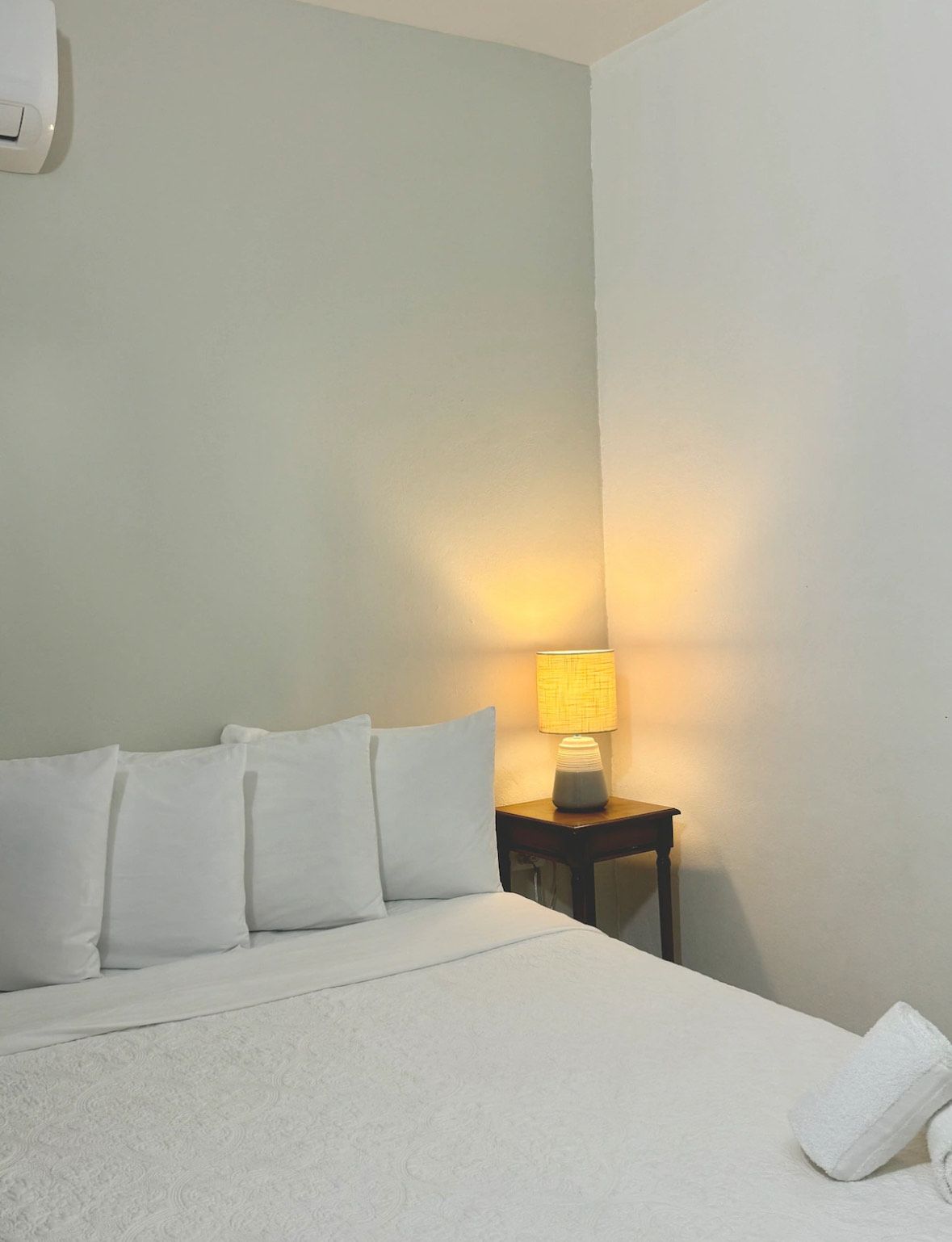 A bedroom with a bed and a lamp on the nightstand