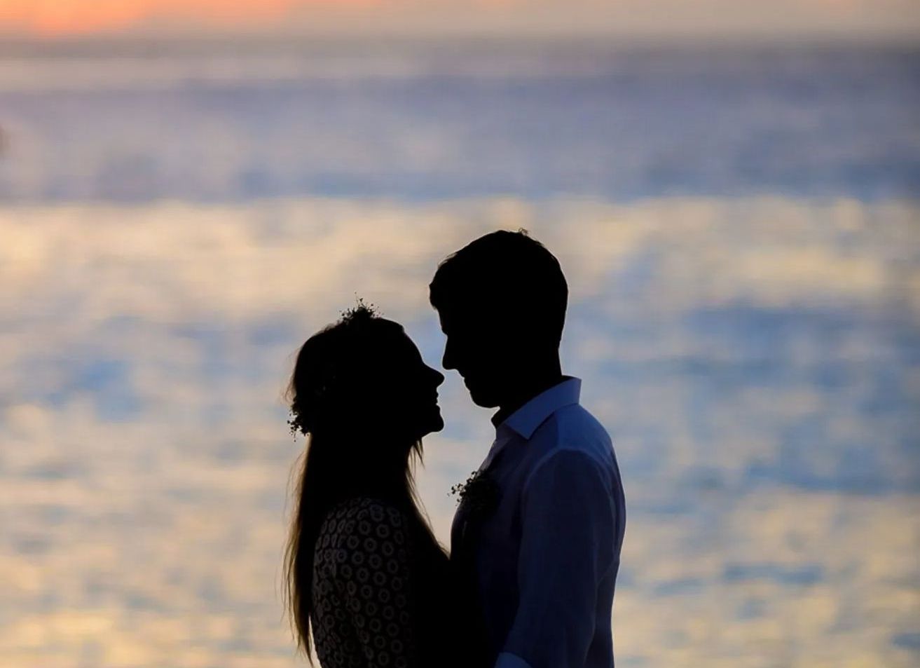 A man and a woman are looking at each other on the beach.