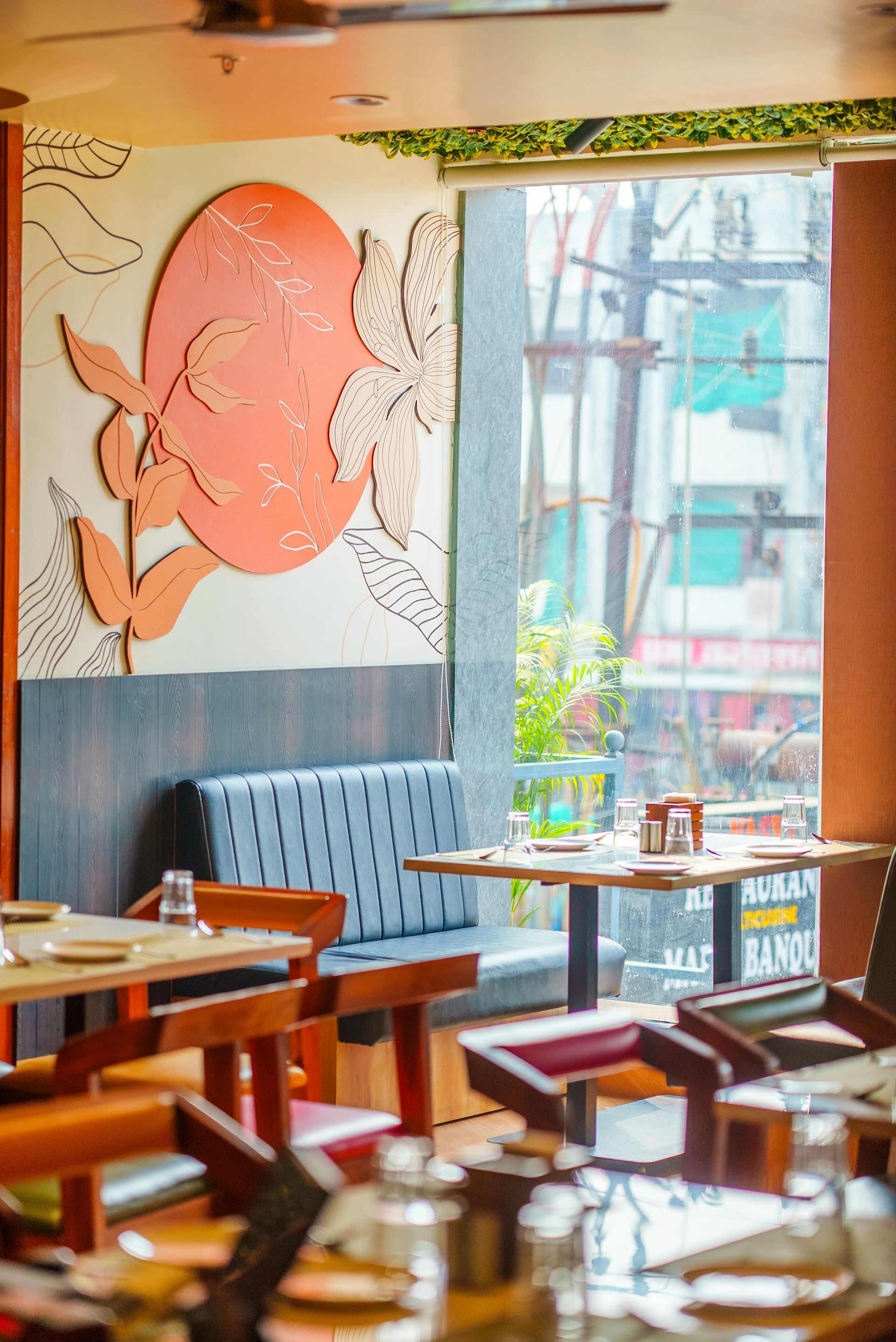 Cozy café interior with blue booth seating, wooden tables, and a large pink floral wall mural